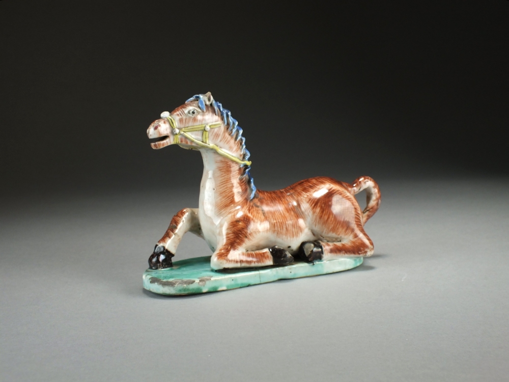 A Chinese famille verte figure of a recumbent horse, 18th Century,