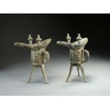 A pair of Chinese bronze ritual vessels, Jue, each libation cup raised on three splayed feet,