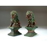 A pair of Chinese sancai glazed figures of lion dogs, 19th century, modelled seated on plinth bases,