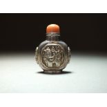 A silver snuff bottle, 19th Century, of compressed ovoid form with buddhistic mask handles,