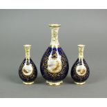 A garniture of three Coalport porcelain cobalt and gilt pear shape landscape vases titled 'Loch
