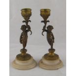A pair of bronze ormolu candlesticks in the form of putti holding cornucopia,