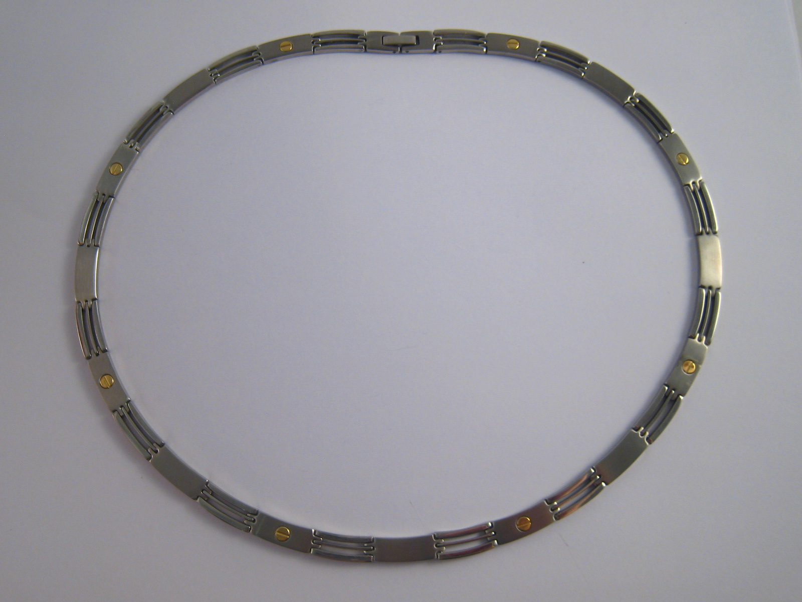 A stainless steel collar necklace with yellow metal (tests 18 carat gold) "screws",
