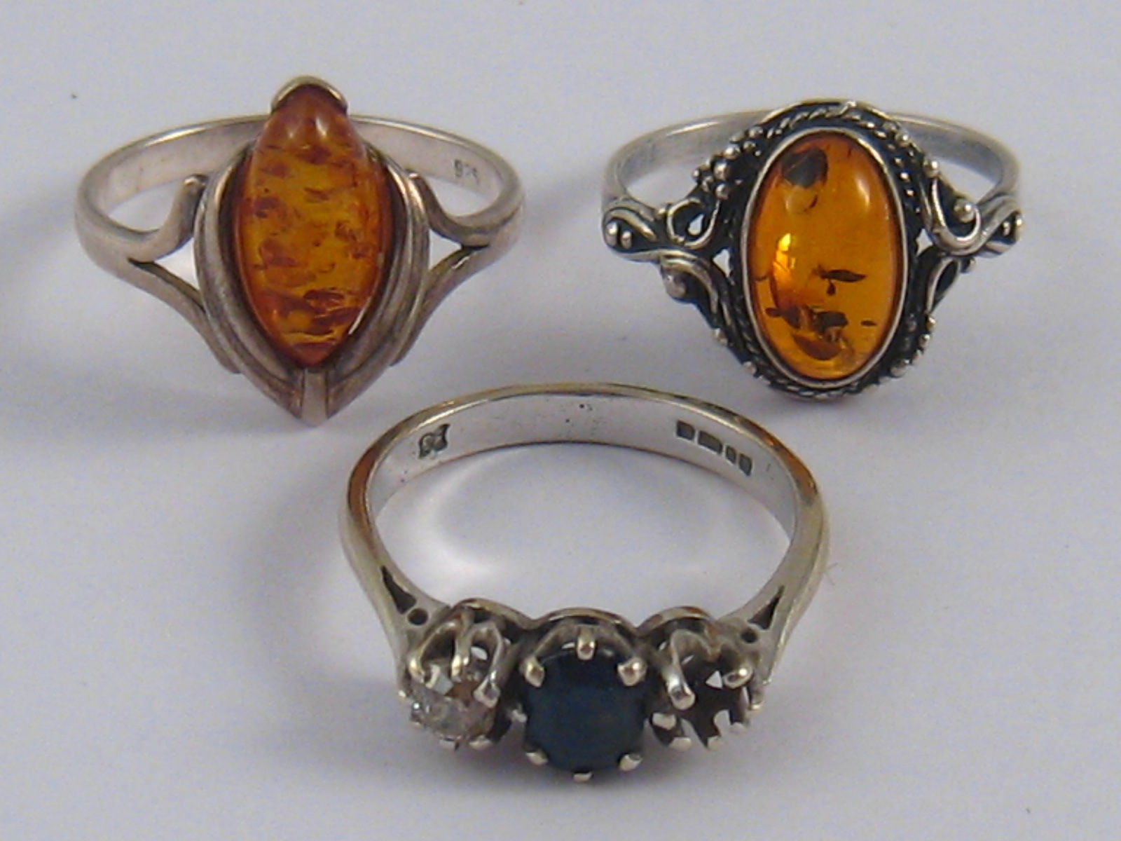 A mixed lot comprising two white metal (tests silver) amber rings,