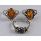 A mixed lot comprising two white metal (tests silver) amber rings,