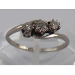 A white metal (tests platinum) three stone old brilliant cut diamond ring,