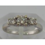 A white metal (tests 18 carat gold) three stone diamond ring,