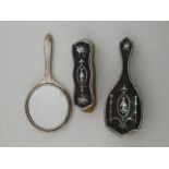 Two silver mounted tortoiseshell brushes and a silver plate mounted hand mirror.