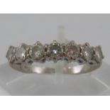 A white metal (tests 18 carat gold) seven stone diamond ring,