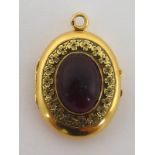 A French 18 carat gold and cabochon garnet locket, the garnet 14.6 x 11mm within a chased border, 2.