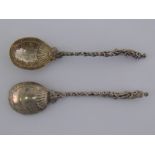 A pair of ornate Victorian silver serving spoons with cast handles of children climbing to a figure