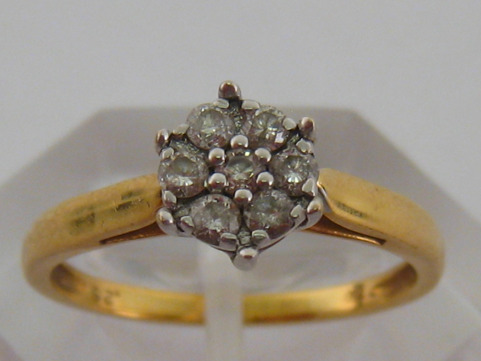 An 18 carat gold and diamond daisy cluster ring, the cluster composed of seven uniform brilliants,