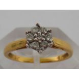 An 18 carat gold and diamond daisy cluster ring, the cluster composed of seven uniform brilliants,