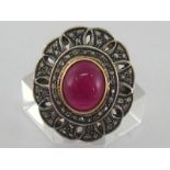 A white metal (tests as silver), cabochon ruby and diamond dress ring,