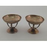 A pair of Edwardian Scottish hammered silver bonbon dishes each with three armed supports over a