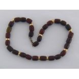 A brown jade and yellow metal (tests as 14 carat gold) necklace,