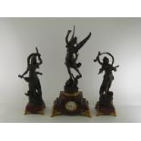 A large clock garniture, the central clock a bronzed finish figure of winged abundance, incised “E.
