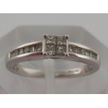 An 18 carat white gold and diamond ring, set to the centre with a square of four calibre cut stones,