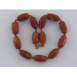 A honey jade necklace, the facetted barrel shaped beads between citrine and yellow metal spacers,