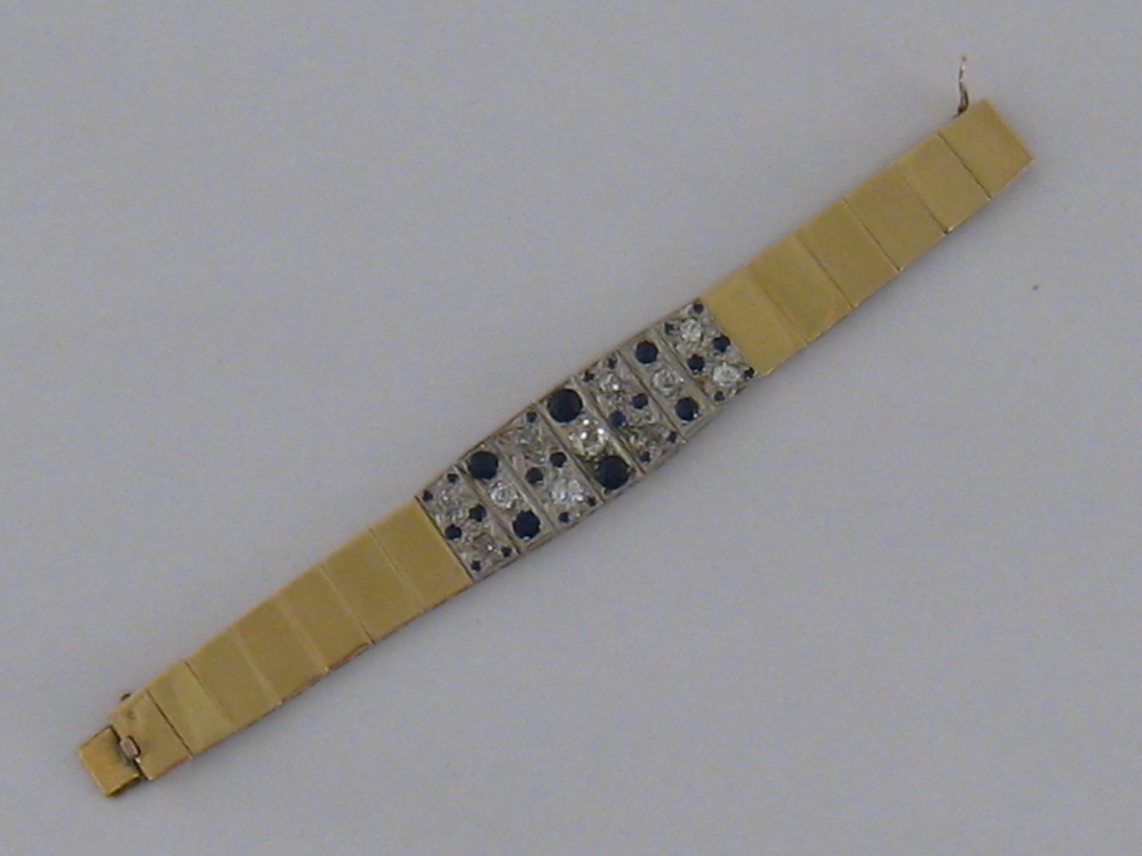 A rose coloured metal (tests as 9 carat gold) sapphire and diamond panel bracelet,