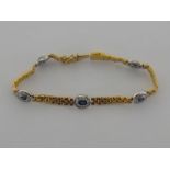 An 18 carat yellow and white gold, sapphire and diamond line bracelet,