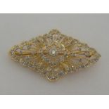 An 18 carat gold and diamond brooch, the open work filifgree mount pavé set overall with brilliants,