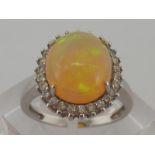 An 18 carat white gold, opal and diamond ring, the large domed cabochon opal 11.9 x 10.