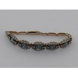 An Art Deco blue topaz line bracelet, the five graduated stones within a surround of white stones,