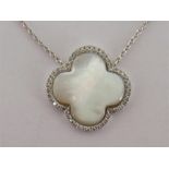 A white metal (tests 18 carat gold) mother of pearl and diamond pendant in the style of Van