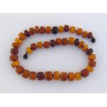 An amber necklace, composed of graduated polished barrel shaped beads, individually knotted, on a