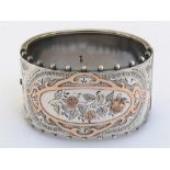 A Victorian silver and rose gold cuff bangle, Birmingham 1886, the front engraved with flowers