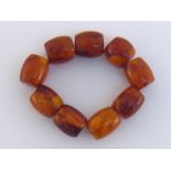 An amber bracelet, composed of nine barrel shaped beads, on an elasticated thread, 84gms