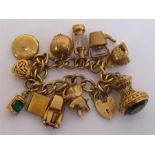 A 9 carat gold charm bracelet, the curb link bracelet suspended with eleven charms (nine fully