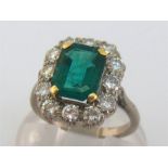 A synthetic flux-melt emerald and diamond cluster ring, the central emerald cut stone 9 x 7 x 4.6