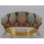 A mid 20th century opal and diamond ring, the five graduated oval opals (the central stone a