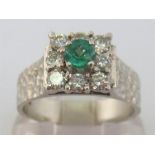 A 1970s 18 carat white gold, emerald and diamond ring, the central round cut emerald 4.1mm diameter,