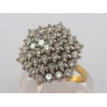 An 18 carat gold and diamond cluster ring, the large hexagonal tiered cluster composed of thirty-