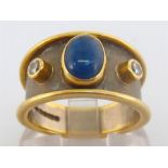 An 18 carat gold, sapphire and diamond ring, the central oval cabochon sapphire 7.6mm long, above