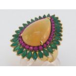 An opal, emerald and ruby dress ring, the central pear shaped cabochon opal approx. 6.62 carat, in a