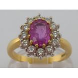 A pink sapphire and diamond ring, the central oval cut stone 8.1 x 6mm, in a surround of