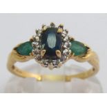 A sapphire and emerald ring, the central oval cut sapphire 6 x 4mm, in an illusion surround, the