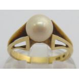 A cultured pearl ring, the single round pearl 7mm diameter, above a winged setting, the shank