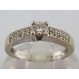 A diamond ring, the small central claw set brilliant approx. 0.17 carat, to pave set shoulders,