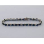 A sapphire and diamond line bracelet, composed of alternate 4.9mm oval cut sapphires and pairs of