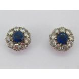 A pair of sapphire and diamond cluster ear studs, each central round cut sapphire 6.7-6.8mm