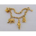 A gold charm bracelet, the anchor link chain set along its length with five charms (two unmarked,