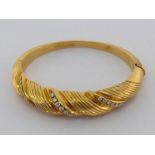 An 18 carat gold and diamond bangle, of writhen design, set with three bands of graduated