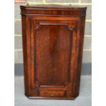 AN ANTIQUE COUNTRY OAK HANGING CORNER CABINET with single drawer.