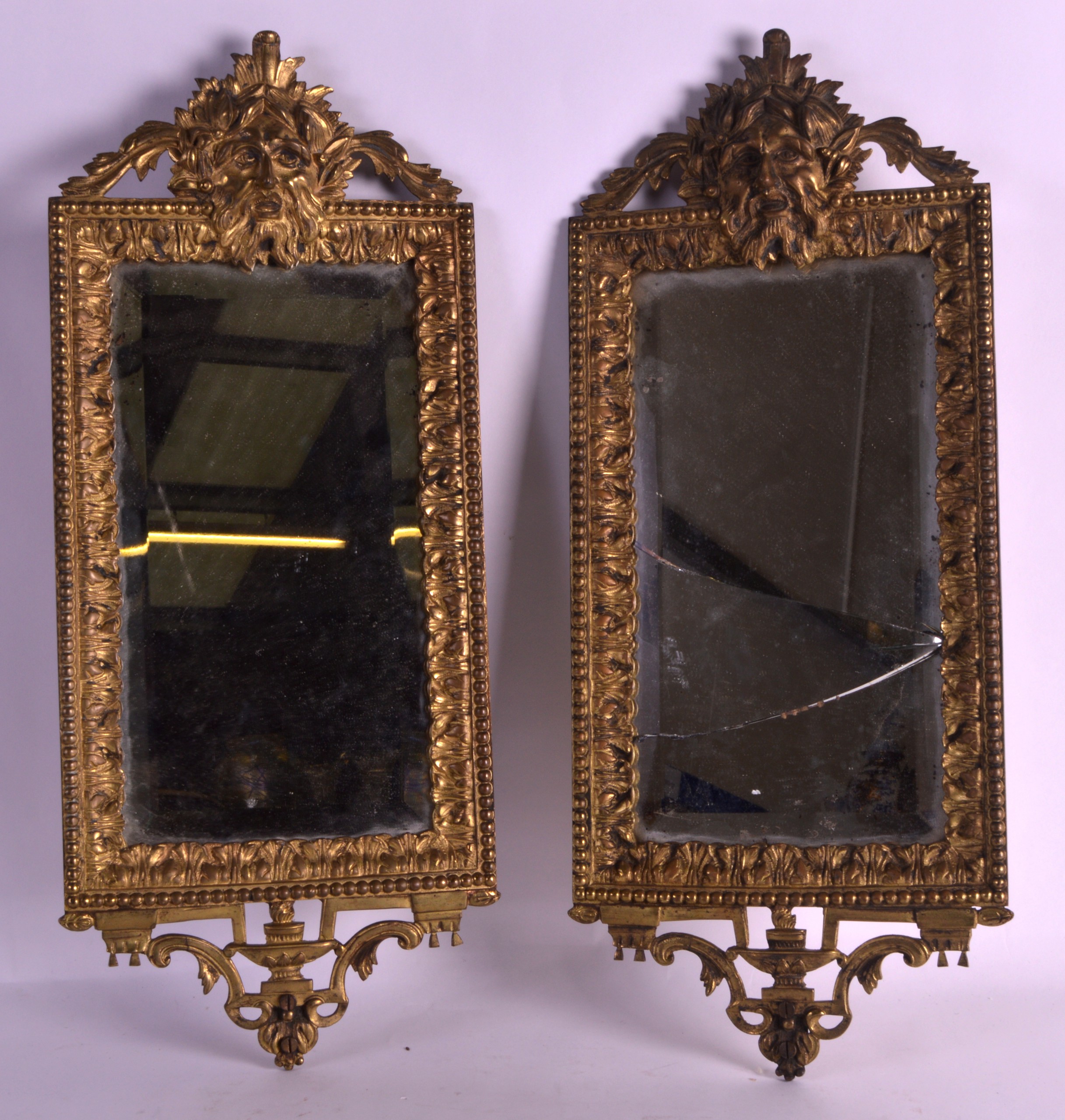 A PAIR OF 19TH CENTURY FRENCH GILT METAL MIRRORS the tops formed as portrait mask heads, within an