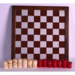 A MID 19TH CENTURY CARVED EUROPEAN IVORY DRAUGHTS SET contained on a later chess board. (qty)